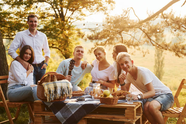 istock Sitting by picnic table. Group of young people have vacation outdoors in the forest. Conception of weekend and friendship 1329525725