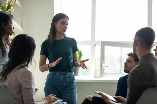 istock Serious female young business coach, team leader speaking before group 1329526357