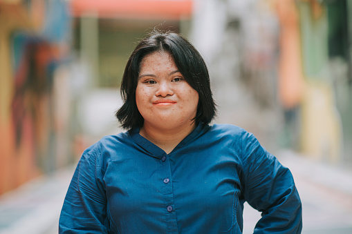 feliz autismo malayo asiático síndrome de Down mujer mirando a la cámara sonriendo en la calle de la ciudad photo