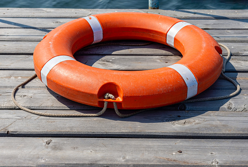 The lifebuoy is lying on a wooden pier. The concept of saving drowning on the water.