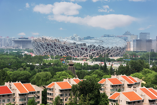 Beijing, China - May 24, 2012: A view of Beijing National Stadium (The Bird’s Nest) Stadium located on Olympic Green, Beijing, China. Tourists and locals walk in front of Beijing National Stadium. Some take photos with the stadium. Some buy food and drink from the small shops in front of the stadium. The Stadium is built for 2008 Olympic Games.