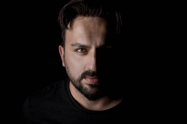 Studio portrait of a handsome man posing against a dark background.
