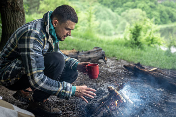 istock A man on a hike sits by the fire and warms himself. 1329530298
