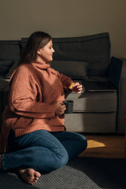 istock Beautiful Plus Size Woman Video Chatting with a Friend Using her Laptop, while Drinking Coffee 1329530933
