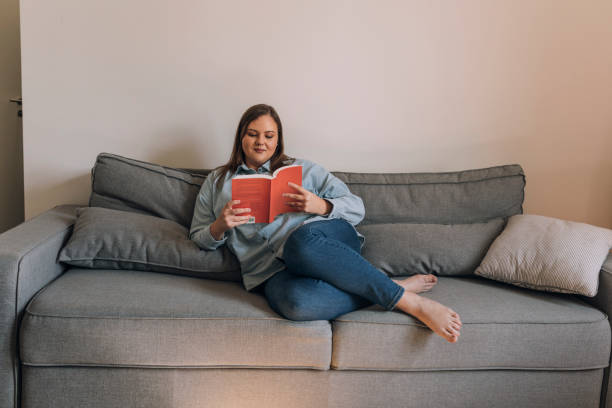 istock Beautiful Plus Size Woman Relaxing on the Sofa and Reading a Book 1329530941