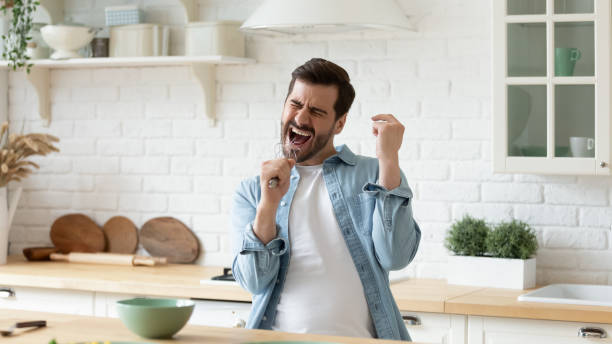 kerl, der schlägert den mund hält, singt gesang in der küche - kitchen utensil audio stock-fotos und bilder