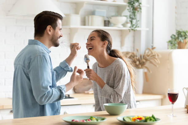 istock Cheery couple holding kitchenware singing having fun together in kitchen 1329531272