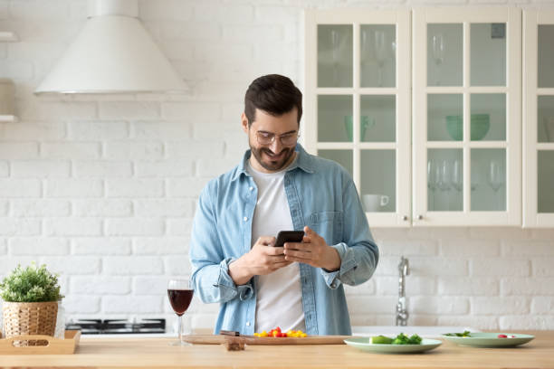 istock Man cooking in kitchen holding smartphone search recipes on internet 1329531279