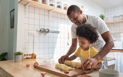 African American Father and son baking at home together. Black Child enjoying helping Dad. Brazilian family in the kitchen.