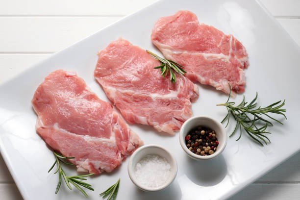 Slices of meat. Veal scaloppini with spices on a white plate. Directly above. scaloppini stock pictures, royalty-free photos & images