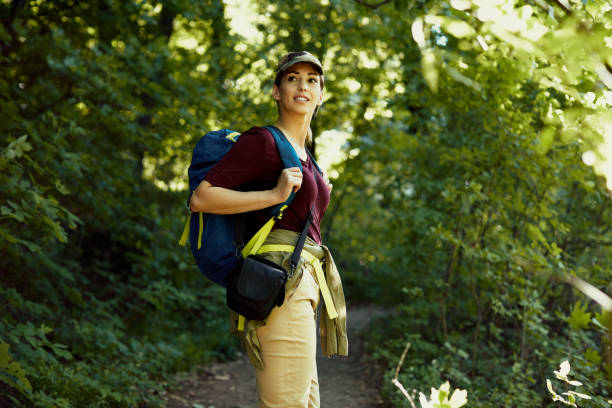 istock Young woman carrying backpack while hiking through the woods. 1329537892