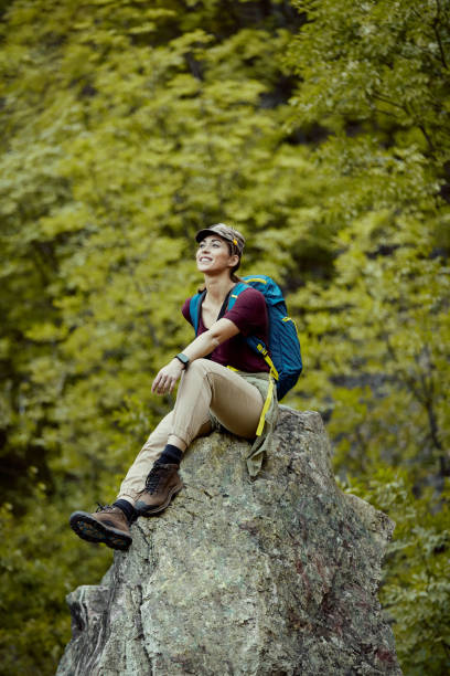 istock Happy female hiker relaxing on a mountain rock. 1329538807