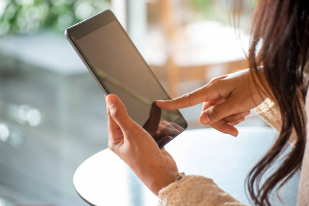 istock Woman's hand Using phone and touch screen at home. Asian Woman Using phone and touch screen, Happy Thai Girl sitting and working online via tablet at home. technology Concept. 1329539540