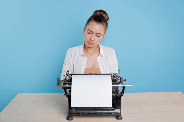 istock young woman author at a typewriter, writes a text. A writer at a table with a vintage typewriter 1329539615