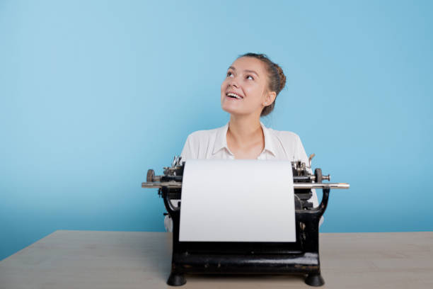 istock happy young woman is an author at a typewriter, is inspired, 1329539630