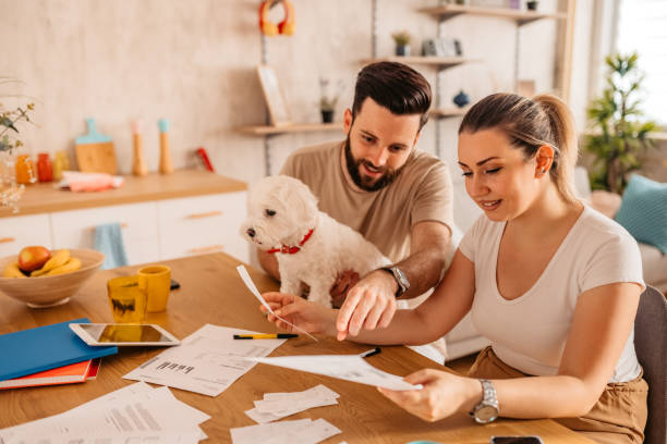 casal verificando suas finanças em casa com seu cachorro - dog insurance - fotografias e filmes do acervo