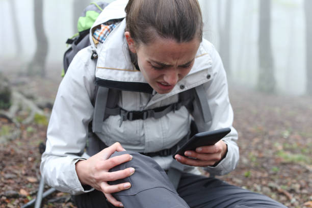 excursionista herido revisando el teléfono inteligente pidiendo ayuda - dropped call fotografías e imágenes de stock