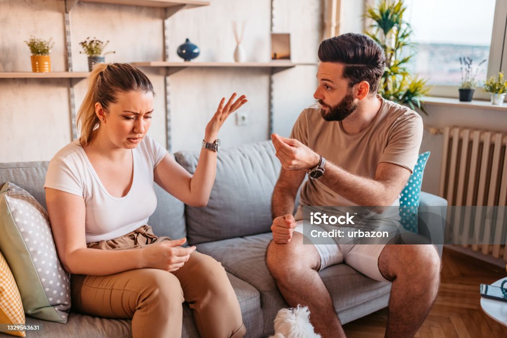 Couple are quarreling at home Young heterosexual couple are quarreling while sitting on couch at home. Couple - Relationship Stock Photo