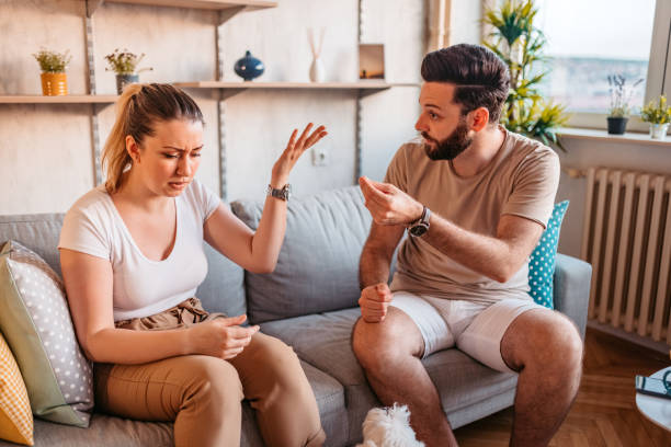 Couple are quarreling at home Young heterosexual couple are quarreling while sitting on couch at home. fighting stock pictures, royalty-free photos & images
