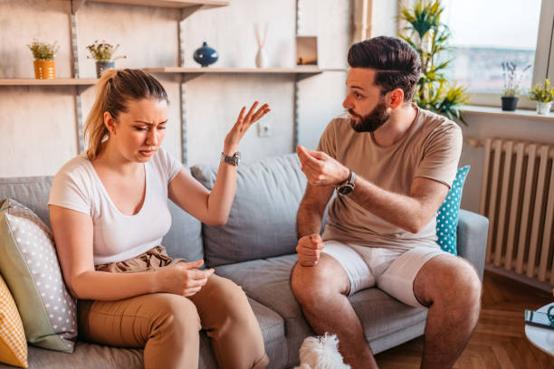 Couple are quarreling at home Young heterosexual couple are quarreling while sitting on couch at home. sulking stock pictures, royalty-free photos & images