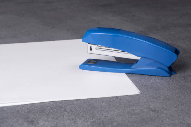 istock Stapler and sheets of white paper close up. 1329548273