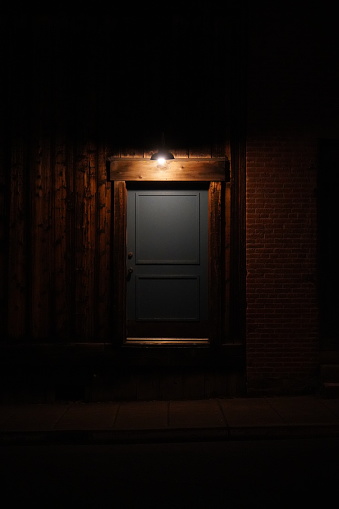 A spooky, dark door on the outside of an old building at night.