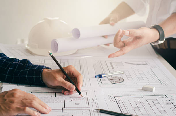istock Close-up view of the engineers' plans being discussed. with architect equipment architect on desk Successful teamwork concept 1329552773