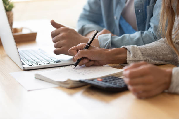 primeros cónyuges calculando el presupuesto familiar que pagan en línea usando la computadora portátil - home finances fotografías e imágenes de stock