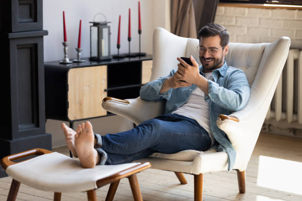 istock Handsome man holding smartphone relaxing on comfy armchair 1329553231