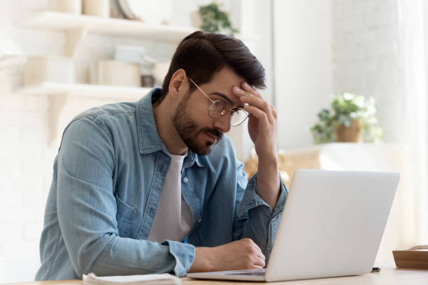 homem olha para a tela do laptop se sente confuso experimentando problemas - sem saída - fotografias e filmes do acervo