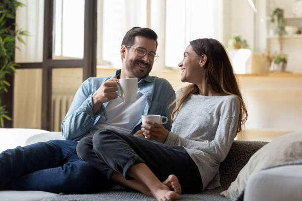 istock Calm relaxed couple holding cups rest on comfy sofa 1329554000