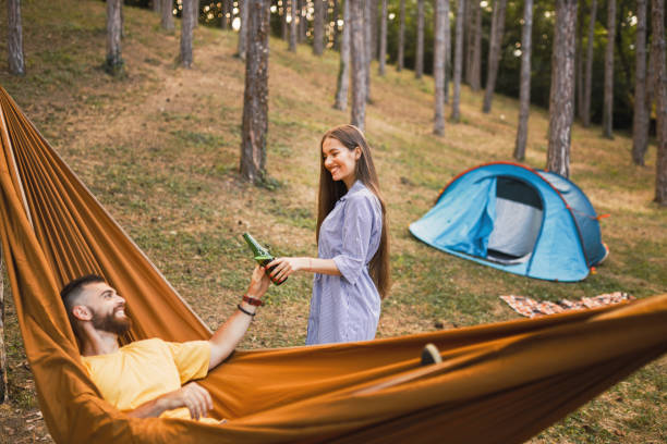 istock Happy couple camping, having fun and drinking beer in forest 1329554894