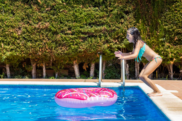 istock Lttle girl jumping on a rubber ring into a pool 1329557743