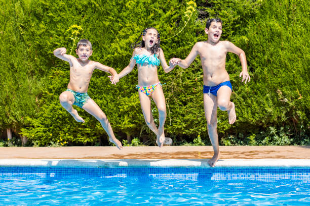 istock Three kids jumping into a pool in a sunny day 1329557775