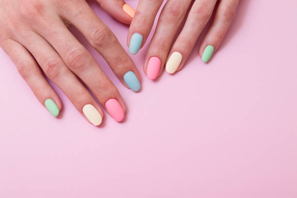 istock Colored matte gel manicure on female hands on a pink background 1329558787