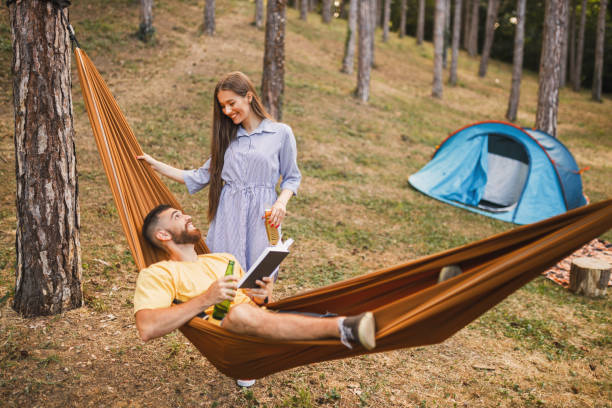 istock Happy couple camping, having fun and drinking beer in forest 1329558946