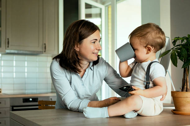 giovane donna con il suo simpatico bambino che si diverte in cucina - baby cup foto e immagini stock