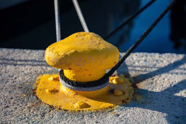 Harbor mooring post, thick ropes around it, blue sea water background.