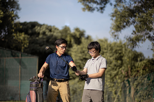 Asia Chinese father guide teenager son golf lesson at golf course