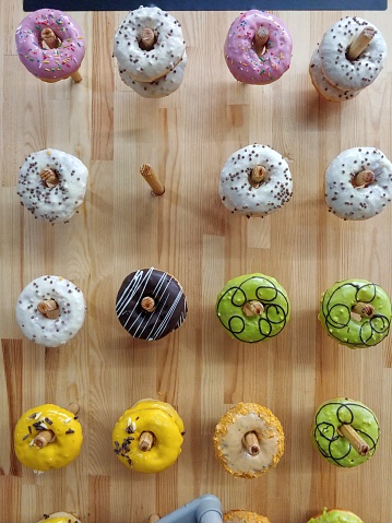 variety of different donuts hanging up on pegs on a wall at pastry shop