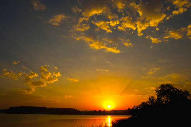 bright summer sunset over the lake in the woods.