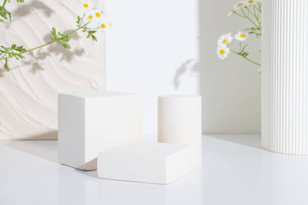 istock Empty podium or pedestal with chamomile flowers on a white background. Blank shelf product standing background 1329566559