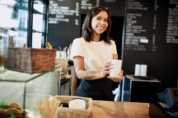 istock Smiling female barista serving takeaway coffee. 1329568711