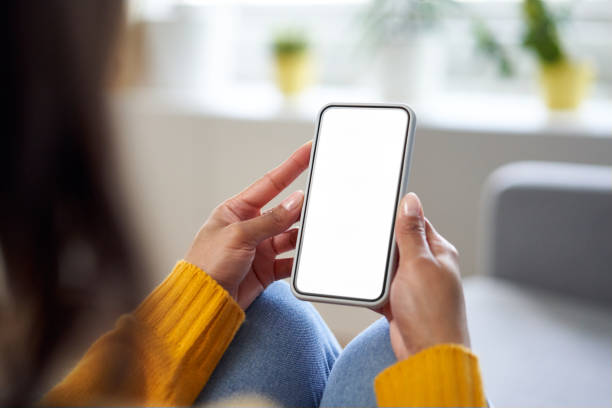 スマートフォンのモックアップ。自宅で空の画面で携帯電話を使用して女性のクローズアップ - 電話機 ストックフォトと画像