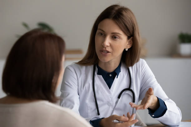 joven médica preguntando a un paciente mayor sobre las quejas - patient medical exam meeting doctor fotografías e imágenes de stock