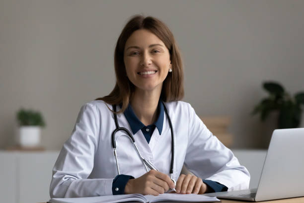 istock Happy confident young female doctor sitting at workplace 1329569955