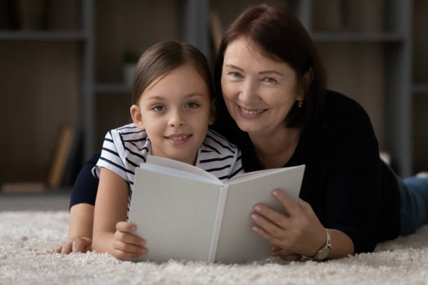 istock Sweet child reading paper book with granny 1329569987