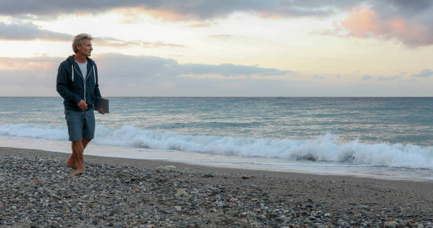 istock Man walks down Mediterranean beach at sunrise 1329570963