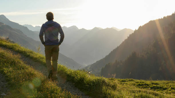 istock Man hikes through grassy meadow in the morning 1329571001