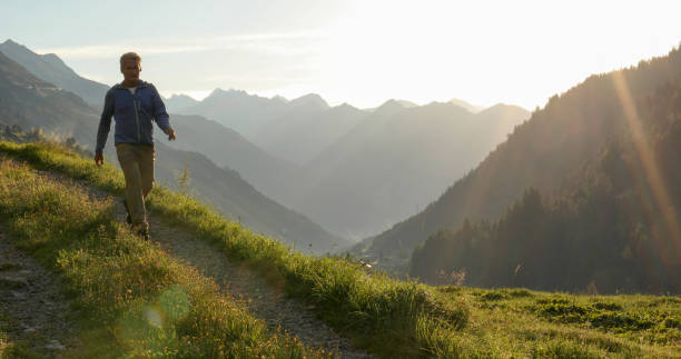 istock Man hikes through grassy meadow in the morning 1329571025